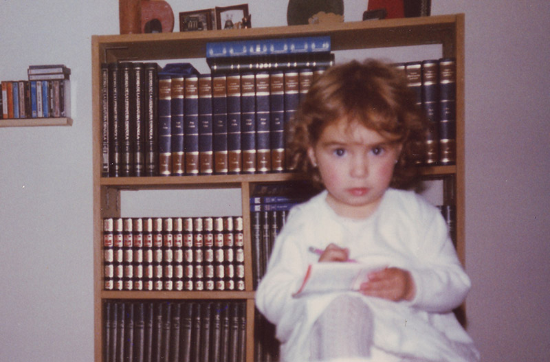 Fotografía de Amelia de pequeña frente a una enciclopedia